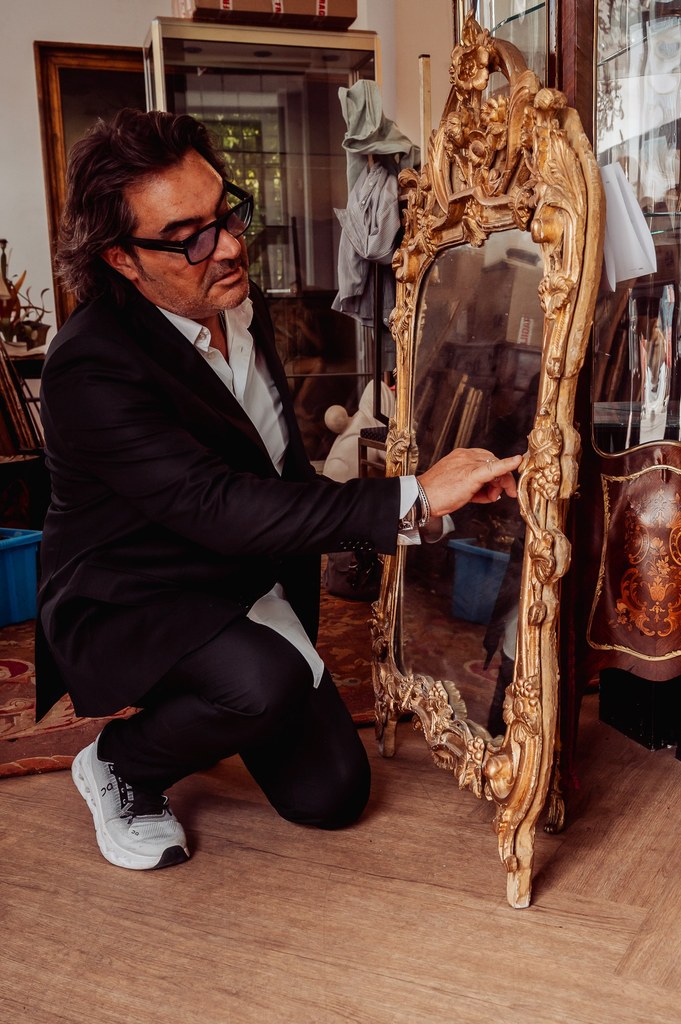 Éric Benhamou examine un miroir ancien doré