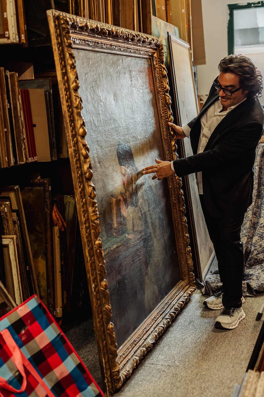 Éric Benhamou désigne le personnage d'une grande toile claire montée dans un cadre baroque doré, dans la réserve des tableaux