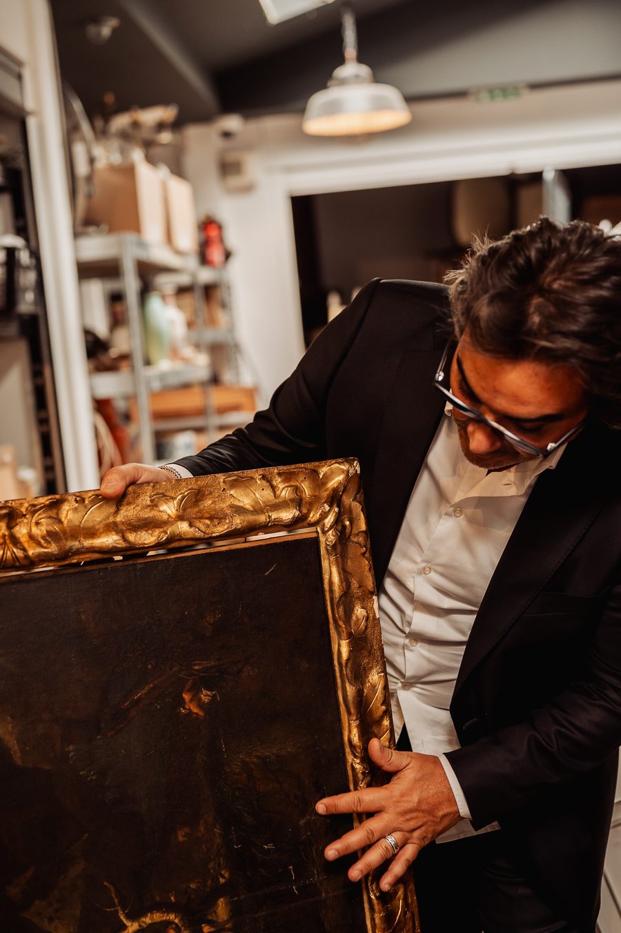Éric Benhamou examine une huile sur toile ancienne et son cadre doré