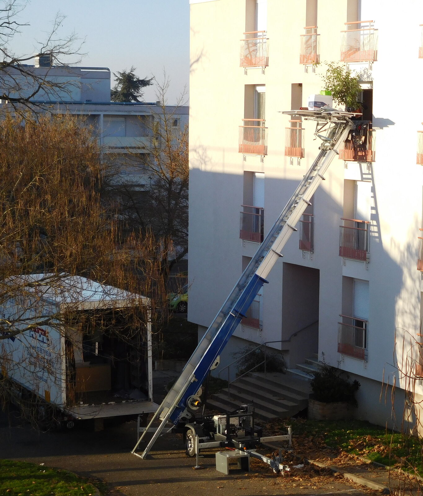 Monte-meubles dressé vers une fenêtre et camion en attente, un jour de déménagement